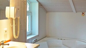 A bathroom with a sink, a mirror, a window, and a bathtub. - Holiday Home in Otterndorf (Otterndorf)