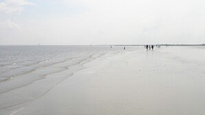 A wide sandy beach with gentle waves, a clear sky, and a distant shoreline. - Holiday Home in Otterndorf (Otterndorf)
