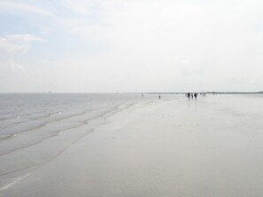 A wide sandy beach with gentle waves, a clear sky, and a distant shoreline. - Holiday Home in Otterndorf (Otterndorf)