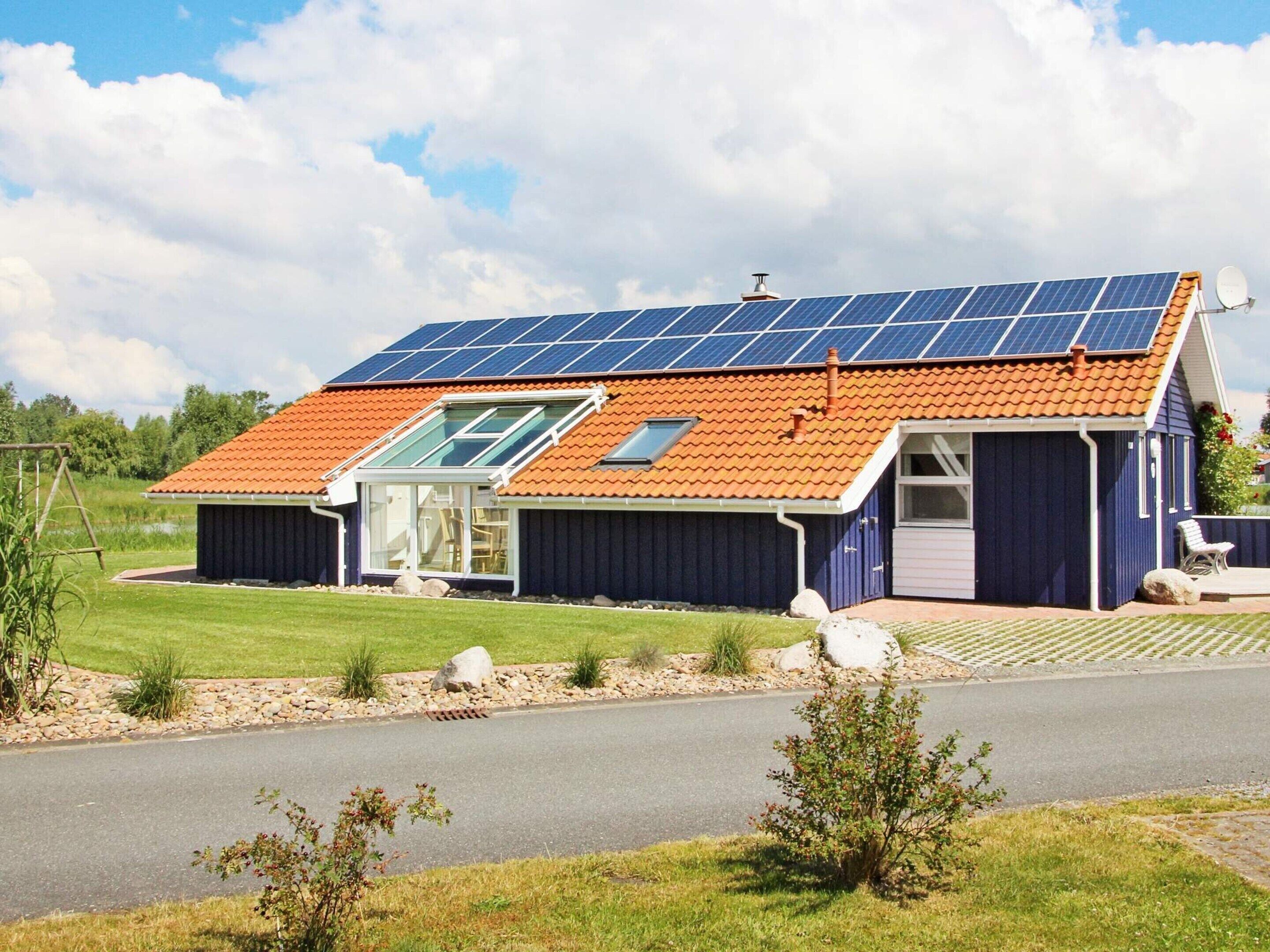 A house with a sloped roof, solar panels, a glass door, and a small porch.