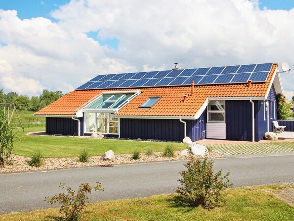 A house with a sloped roof, solar panels, a glass door, and a small porch.