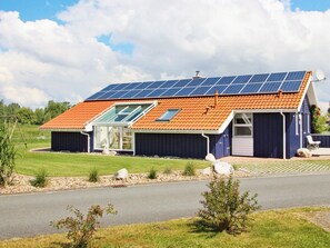 A house with a sloped roof, solar panels, and a small attached garage.