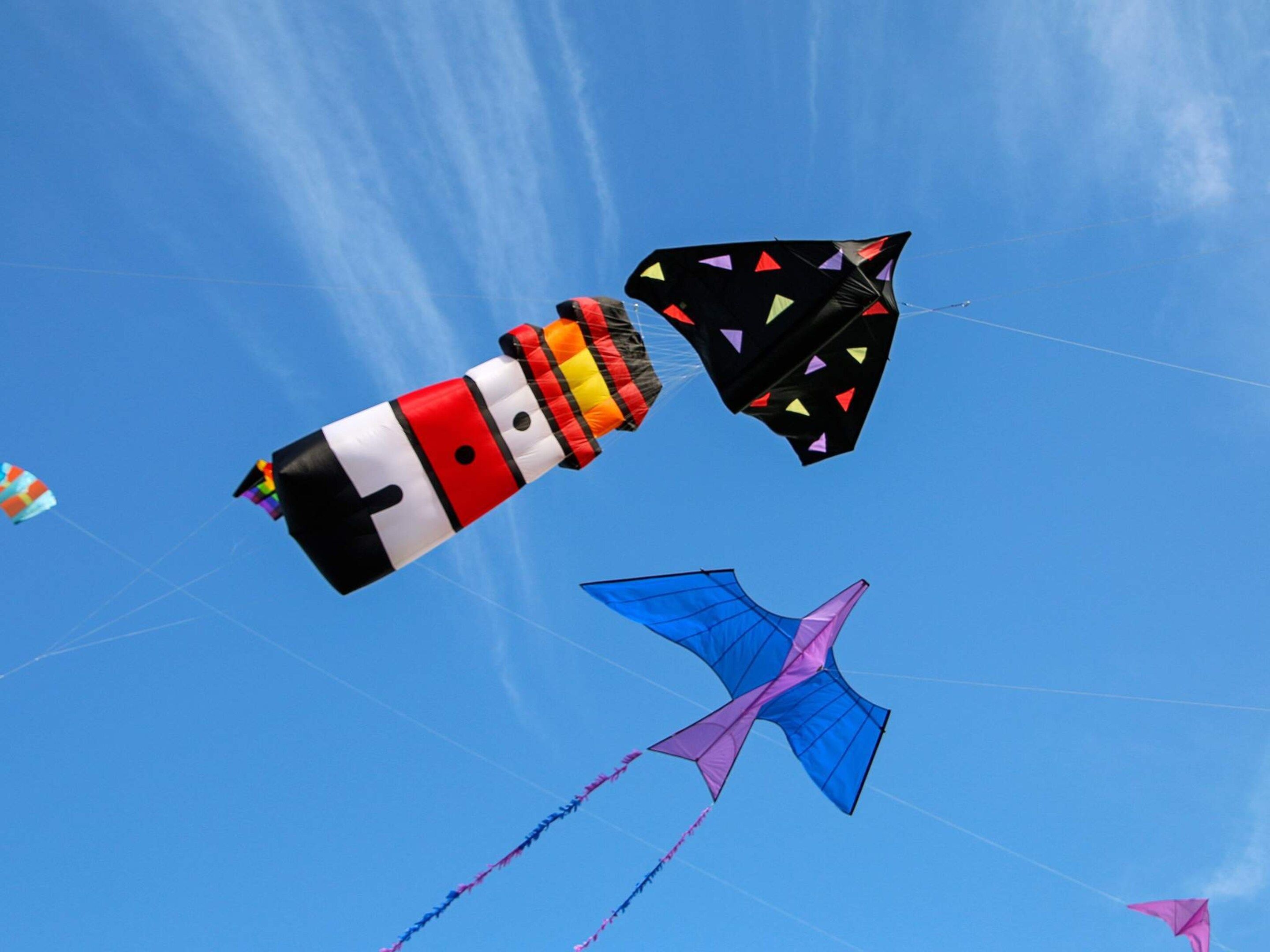 A clear blue sky with multiple kites flying.