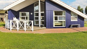 A single-story building with a gabled roof, large windows, and a covered patio area with outdoor furniture. - Holiday Home in Otterndorf (Otterndorf)