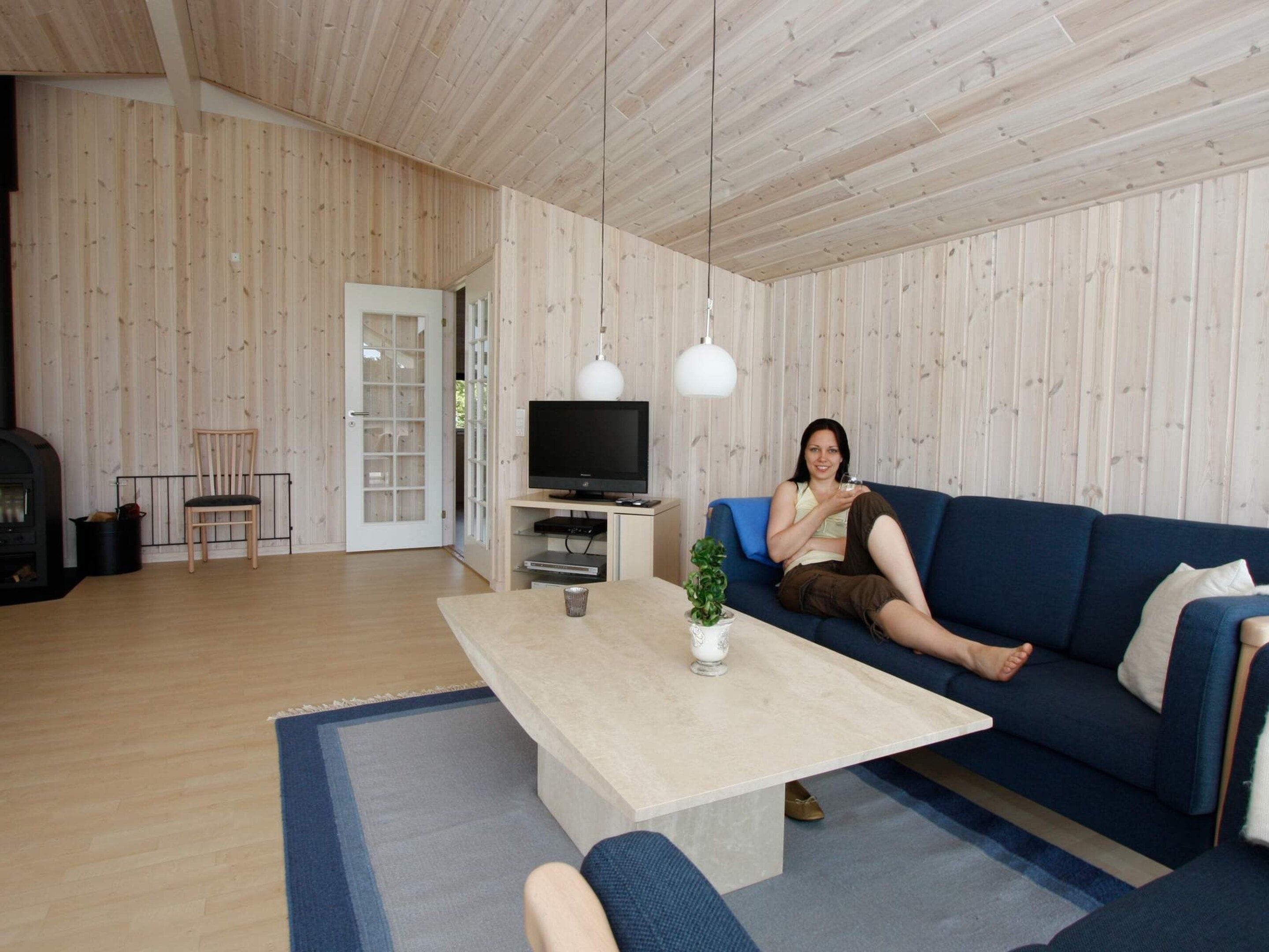 Un salon moderne avec un plancher en bois, un canapé bleu, une table basse, un téléviseur et une cheminée.