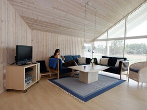 A living room with a television, a sofa, a coffee table, and a large window.