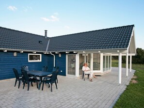 A house with a covered patio, a chimney, and a window overlooking the yard. - Fabulous Holiday Home in Rodby Denmark near Sea (Rodby)