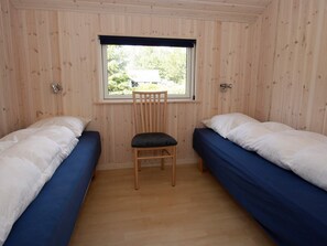 A room with two single beds, a wooden chair, a window, and a door.