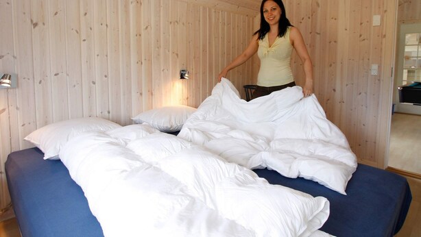 A room with wooden panel walls, a bed with white bedding, and a wall-mounted light fixture. - Fabulous Holiday Home in Rodby Denmark near Sea (Rodby)