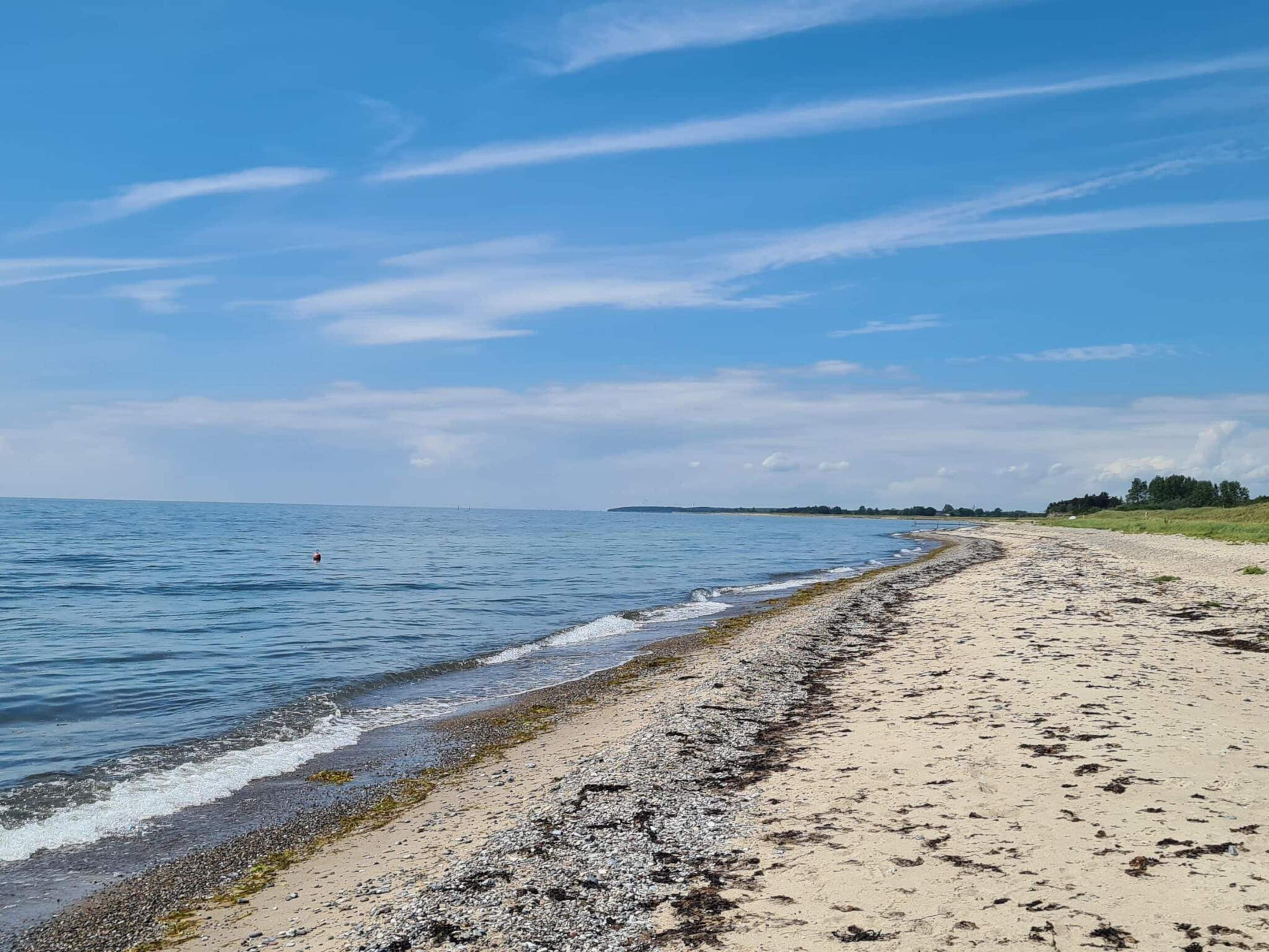 A beach with a pebbly shore and a clear sky.