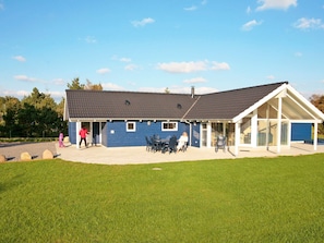 A blue building with a covered patio area and a lawn in front.