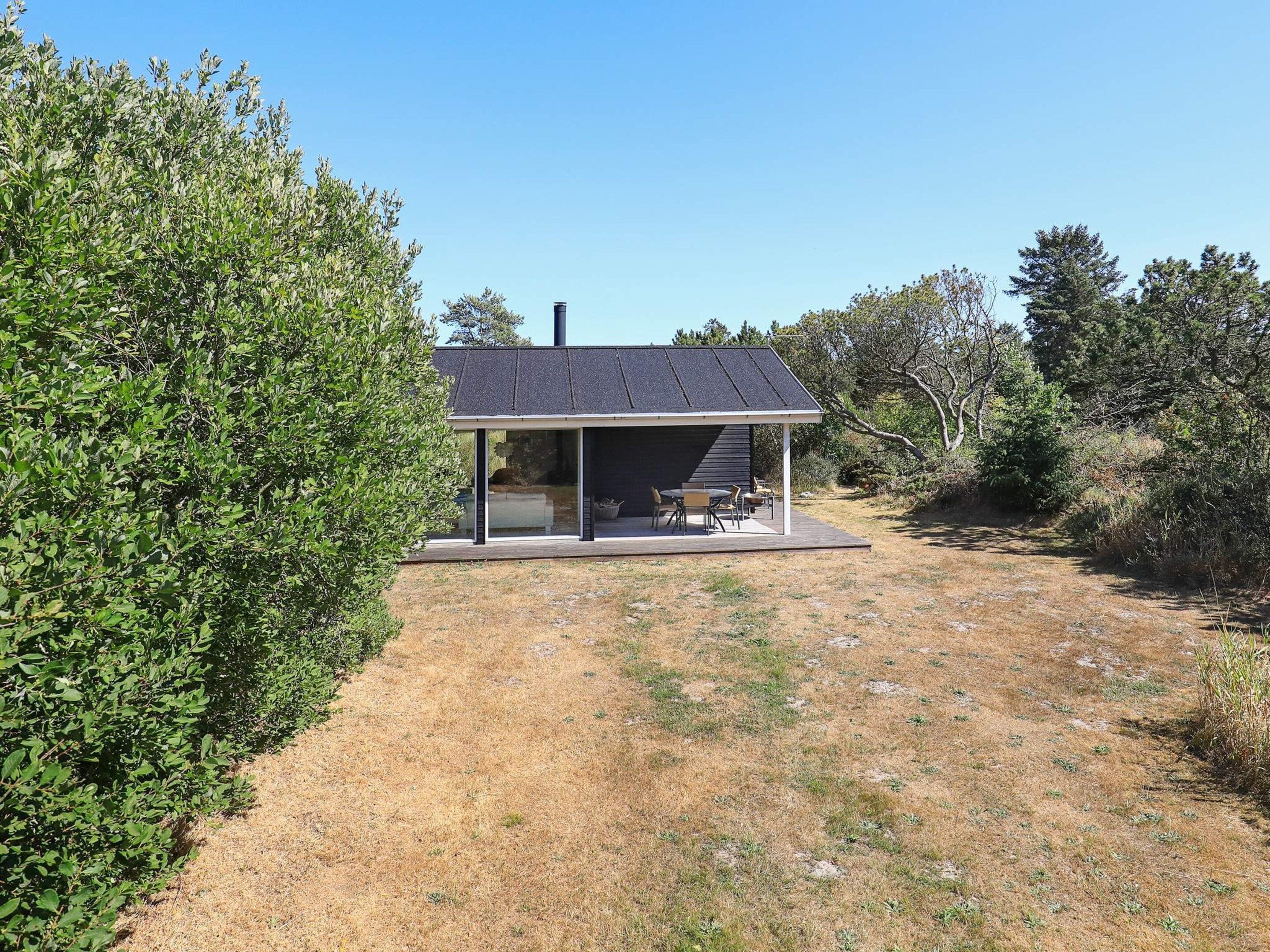 Uma casa moderna com varanda coberta, chaminé e vista para a paisagem ao redor.