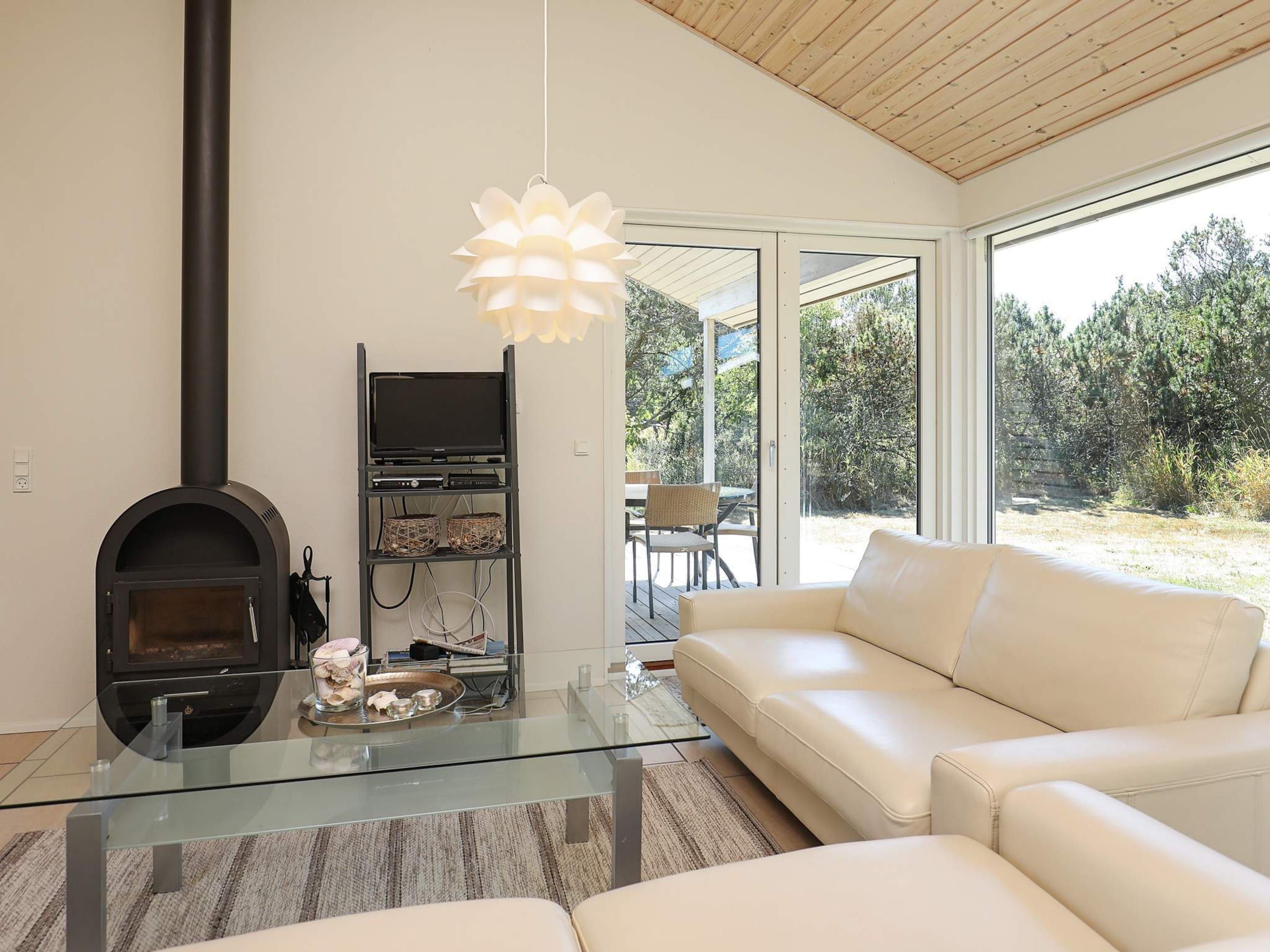 A modern living room with a glass coffee table, a white sofa, a fireplace, and a TV on a black stand.