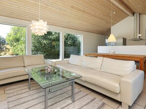 Una sala de estar moderna con una mesa de centro de vidrio, un sofá color beige y una mesa de comedor de madera.