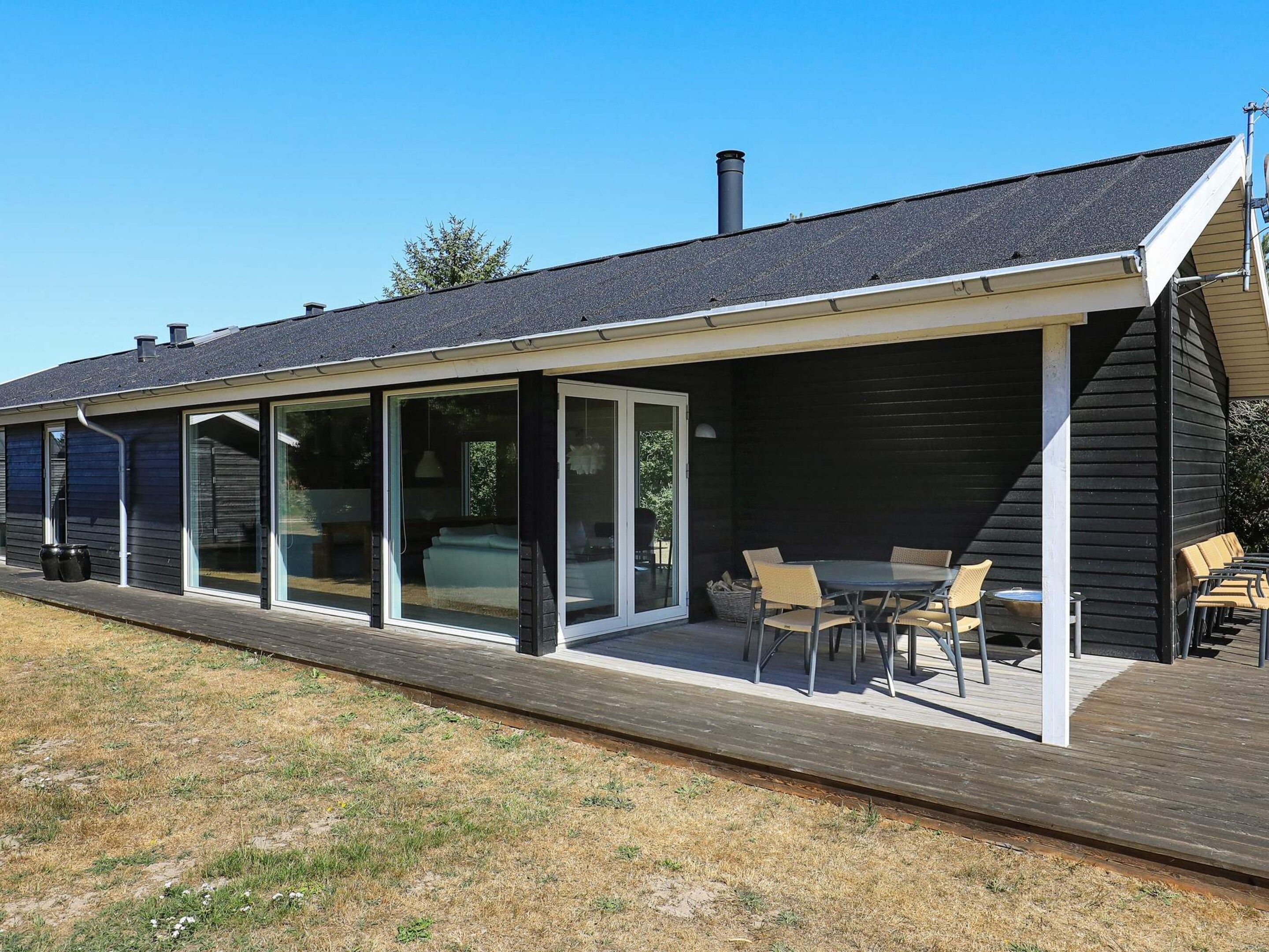 A modern house with a covered patio area featuring a dining table and chairs.