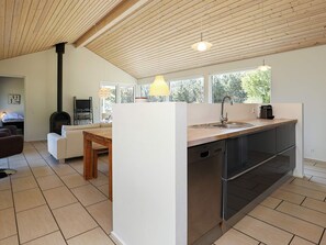 Una cocina moderna con lavavajillas integrado, una mesa de comedor de madera y un amplio ventanal que proporciona luz natural.