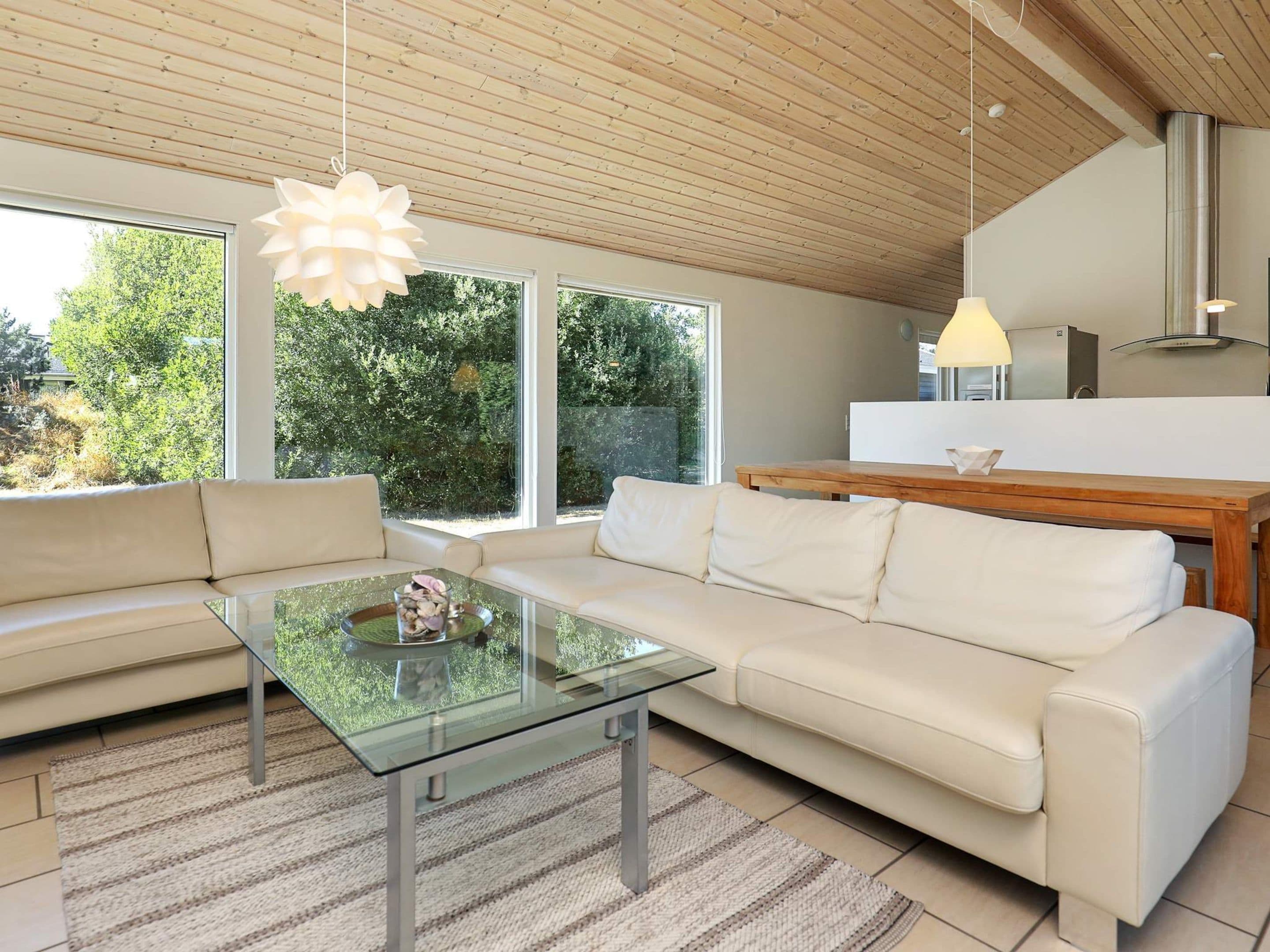 A modern living room with a glass coffee table, a sofa, and a wooden dining table.