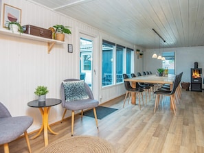 Ein modernes Interieur mit einem Holzesstisch, Stühlen, einer Couch und einem Kamin.