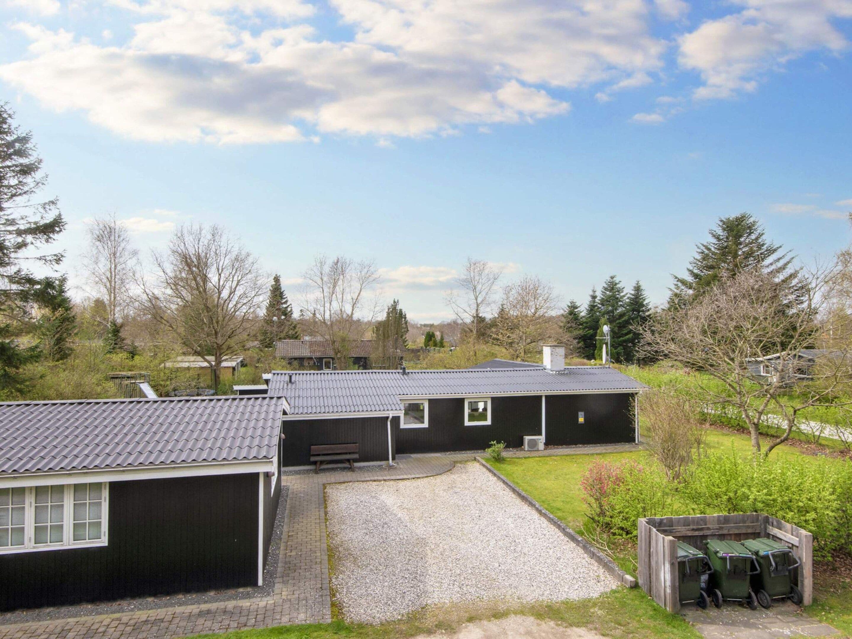 A residential property with a garage, a gravel driveway, and a fenced garden area.