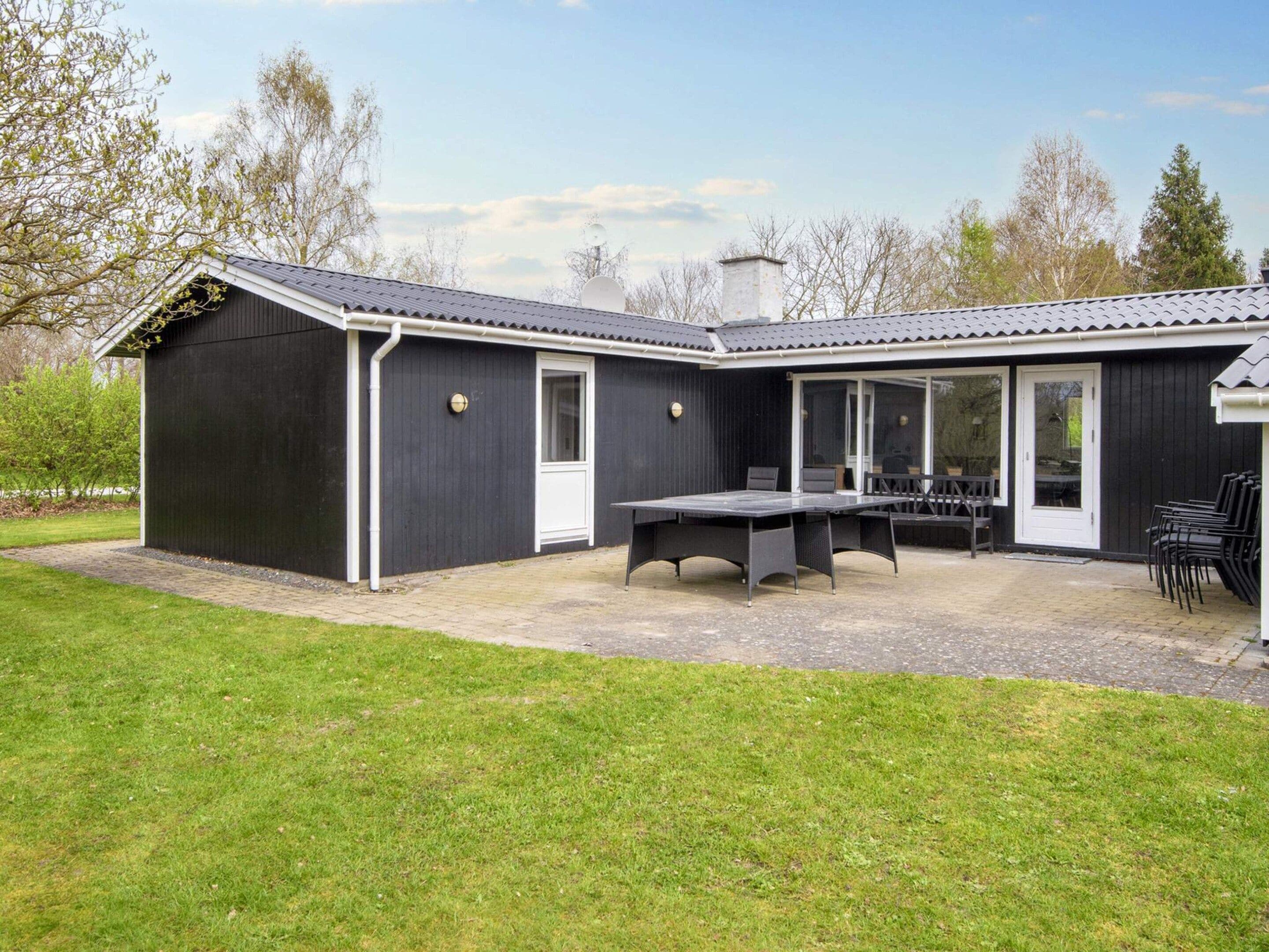 A modern house with a patio area, a dining table, and chairs.
