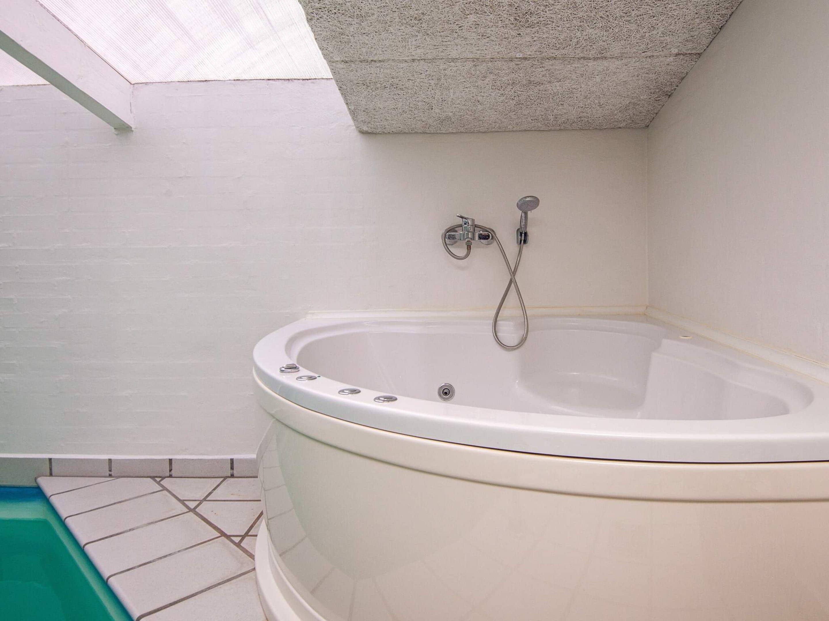 A bathroom with a bathtub, shower, and a skylight.