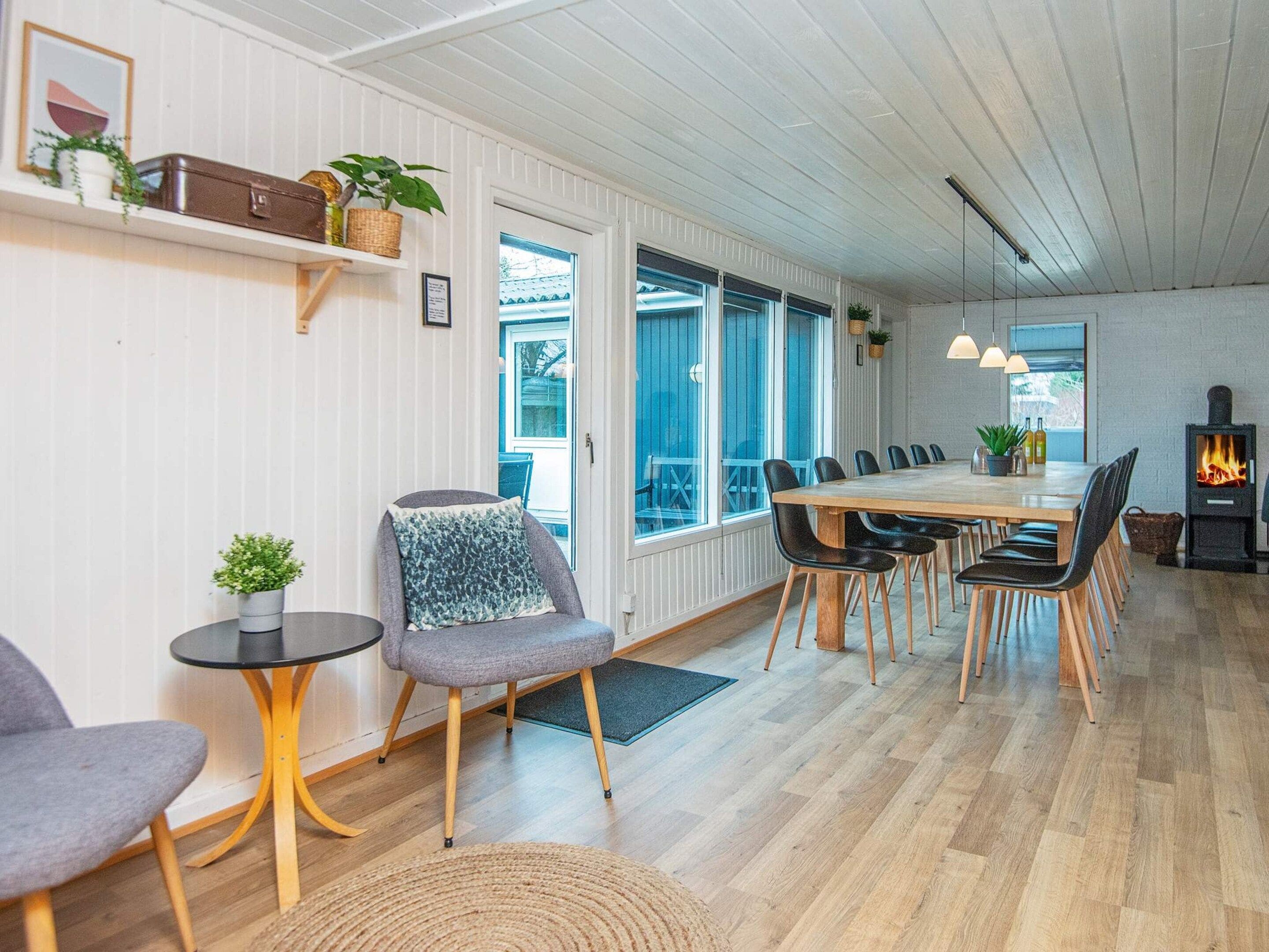 Un interior moderno con comedor, asientos, chimenea y ventanas amplias.