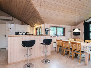 A wooden interior with a kitchen, dining area, and bar stools.