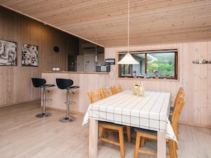 A wooden interior with a dining table, chairs, and a bar area.