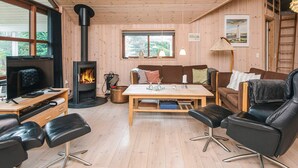 A cozy cabin interior with a wooden interior, a fireplace, a sofa, a coffee table, and a TV. - 4 Star Holiday Home in Blavand (Blavand)