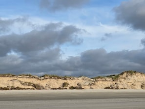 Ein Strand mit sandigem Ufer und einer Düne.