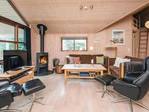 A cozy cabin interior with a fireplace, wooden furniture, a television, and a dining area.