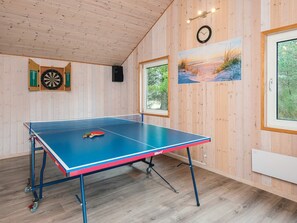 A ping pong table in a room with wooden walls and a window.