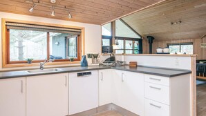A modern kitchen with wooden cabinets, a large window, and a built-in stove.