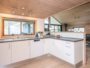 A modern kitchen with wooden cabinets, a large window, and a built-in stove.