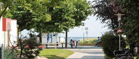 A pathway with bicycles, benches, and a view of the sea.