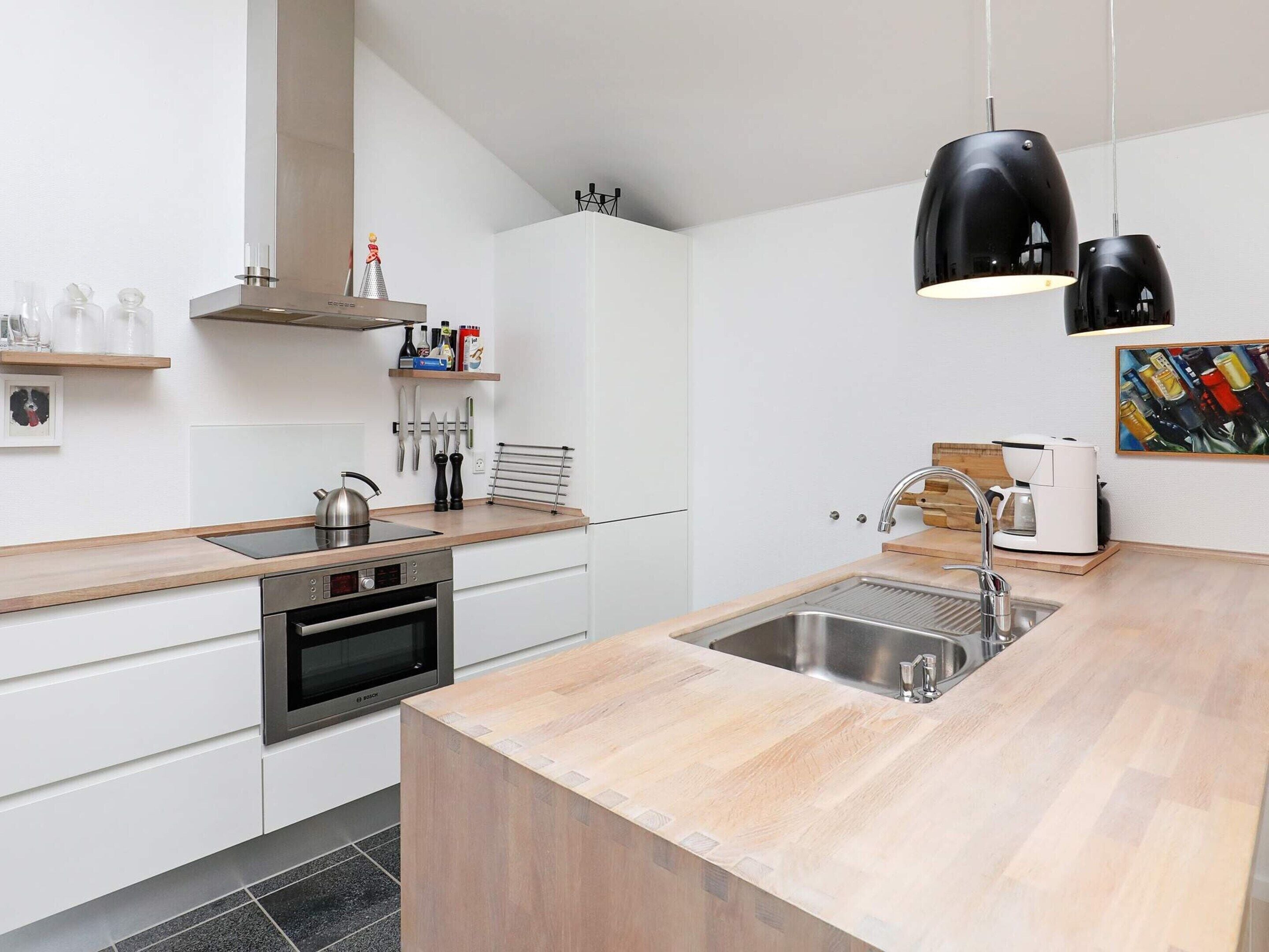 A modern kitchen with a built-in oven, a sink, and a coffee maker.