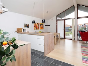 A modern kitchen with a wooden island, white cabinets, and a large window offering a view of the outside. - 4 Star Holiday Home in Bogense (Bogense)