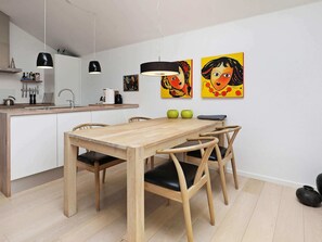 A modern kitchen with a wooden dining table, chairs, and pendant lights. - 4 Star Holiday Home in Bogense (Bogense)