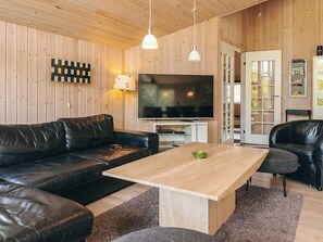 A modern living room with a wooden interior, leather sofas, a flat-screen TV, and a coffee table. - Attractive Holiday Home in Vaggerlose near Sea (Idestrup)