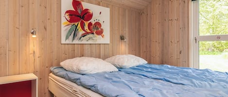 Habitació amb panells de fusta, un llit, una prateleira vermella i una finestra.