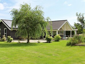 A two-story house with a covered porch and a lawn. - Attractive Holiday Home in Vaggerlose near Sea (Idestrup)