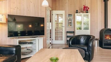 A modern living room with a television, leather sofa, a dining table, and a fireplace.