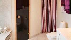 Une salle de bain avec des toilettes, un rideau de douche et un tableau au mur.
