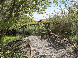 A garden area with a gravel patio, wooden chairs, and a wooden bench. - Attractive Holiday Home in Vaggerlose near Sea (Idestrup)