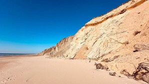 A beach with a sandy shore and a steep cliff.