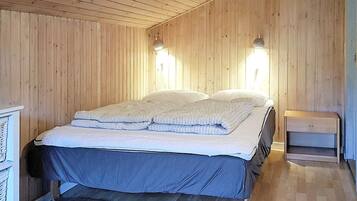 A room with a bed, wooden walls, and two wall-mounted lights.