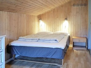 Ein Zimmer mit einem Bett, Holzwänden und zwei Wandleuchten.