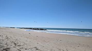 A beach with footprints, waves, and birds.