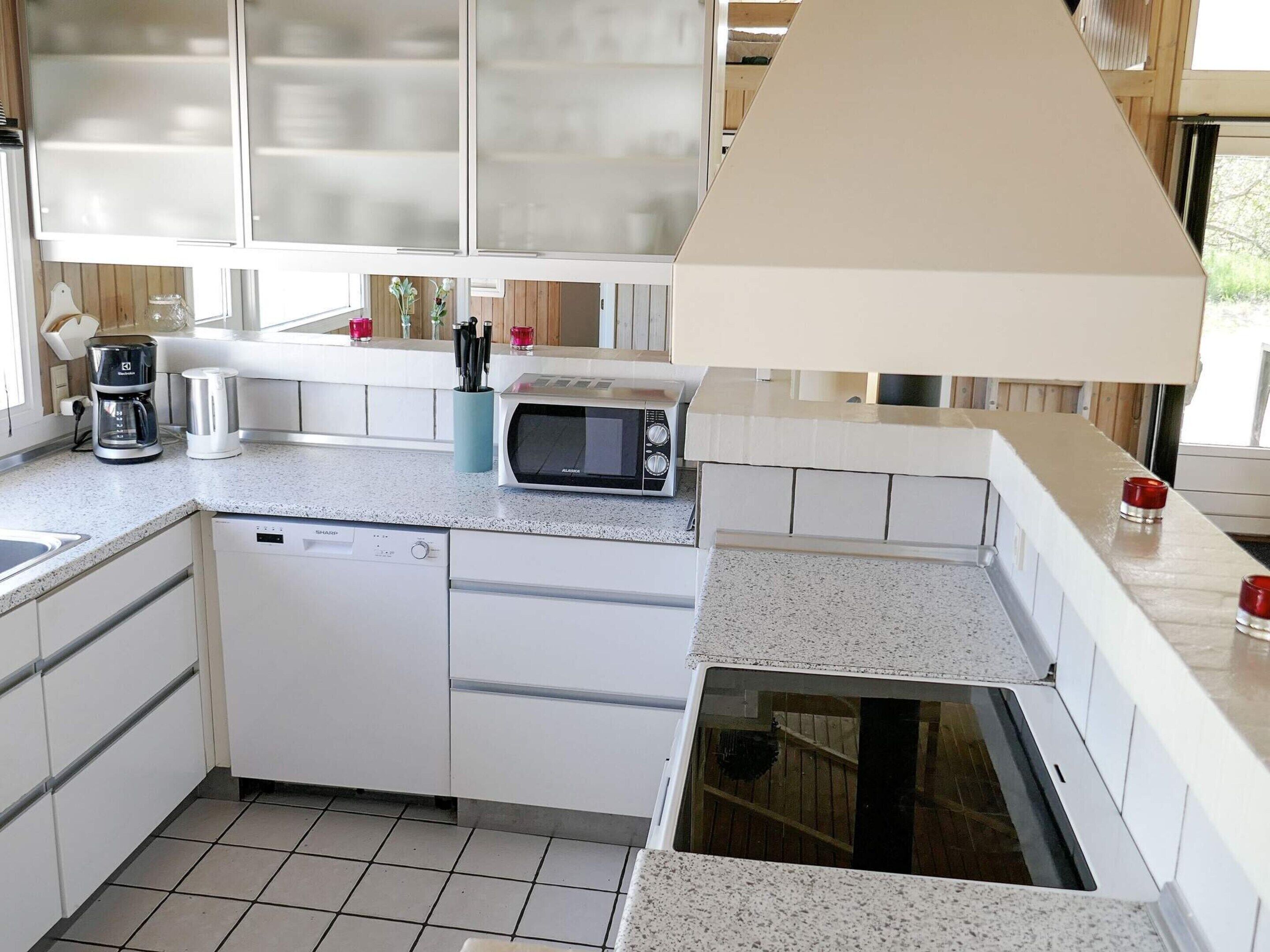 A compact kitchen with white cabinets, a dishwasher, a microwave, and a sink.