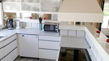 A compact kitchen with white cabinets, a dishwasher, a microwave, and a sink.